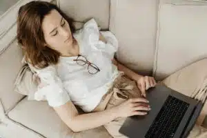 Maman travaillant sur son laptop depuis le canapé pour générer des revenus complémentaires à domicile