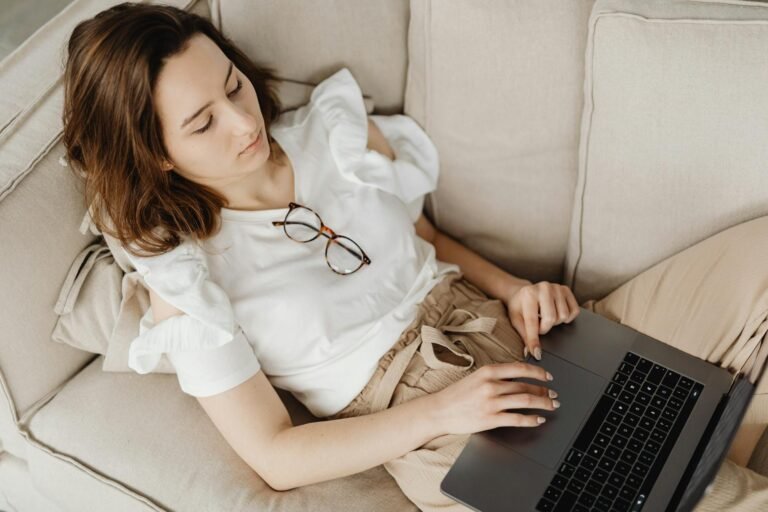 Maman travaillant sur son laptop depuis le canapé pour générer des revenus complémentaires à domicile