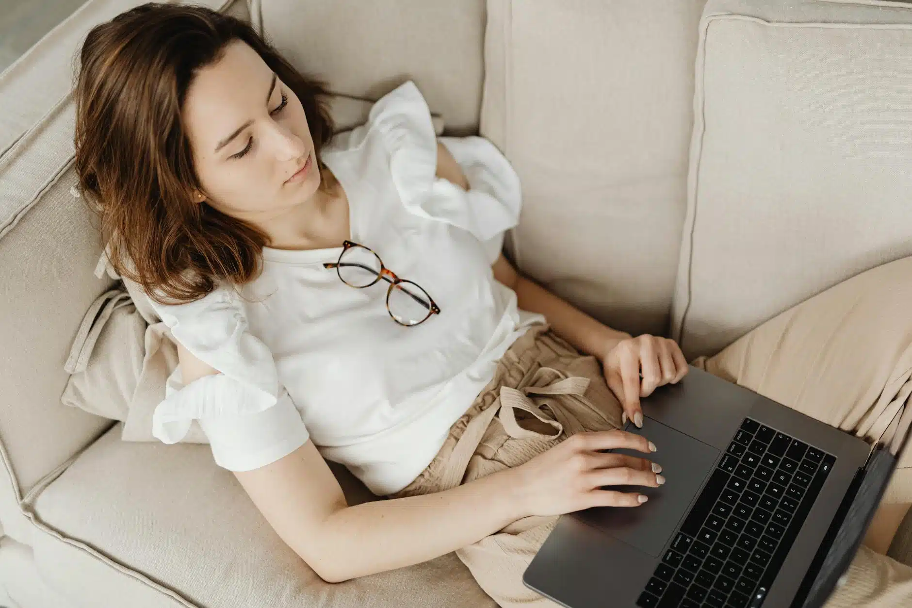 Maman travaillant sur son laptop depuis le canapé pour générer des revenus complémentaires à domicile